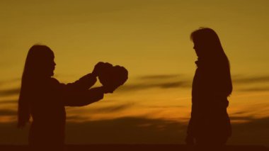 Gün batımında bir çocuğun kalbini annesine vermesi. Çocuklar anneye bayılır. Bir ergenle ebeveyn. Aile ilişkileri kavramı