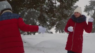 Mutlu çocuk çam parkı içinde karlı beyaz dağda kartopu oynamak. Kar kış orman ve gülümseme ile genç kız oyun