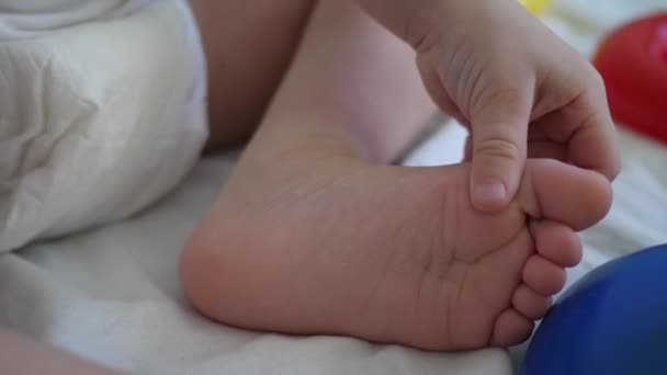 O bebé brinca com os pés. Desenvolvimento de crianças em idade pré-escolar. Close-up — Vídeo de Stock