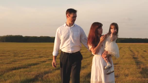 Concetto di infanzia felice. bambino, papà e mamma giocano nel prato al sole. padre e figlioletta, madre, che camminano sul campo al sole. Una giovane famiglia felice. concetto di una famiglia felice . — Video Stock