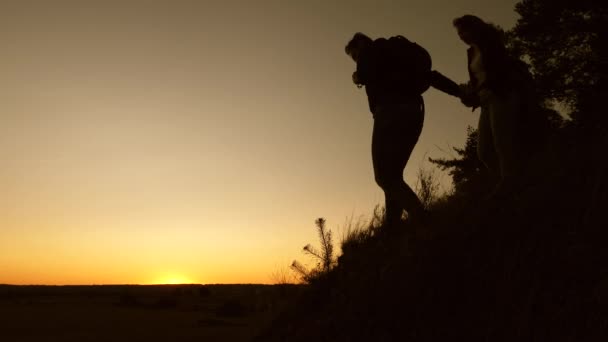 Viajero masculino y viajero femenino descienden desde la cima de la colina. trabajo en equipo de gente de negocios. los turistas descienden de la montaña al atardecer, uno tras otro. Familia feliz de vacaciones . — Vídeos de Stock