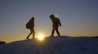 Dağcılar karlı dağın tepesinde karşılamak ve onların başarısı zevk, ellerini kaldır ve sevinçle atlamak. Sırt çantaları ile erkek turistler kış günbatımı bir tepeye ulaştı. spor turizm kavramı