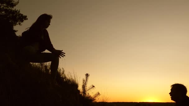 Viajante do sexo feminino segura a mão de um viajante do sexo masculino ajudando a subir no topo da colina. Os turistas escalam a montanha ao pôr do sol, de mãos dadas. trabalho em equipe de parceiros de negócios. Família feliz em férias . — Vídeo de Stock