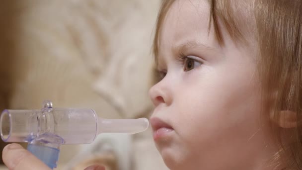 Little girl treated with an inhalation mask on her face in a hospital. child is sick and breathes through an inhaler. Toddler treats flu by inhaling inhalation vapor. — Stock Video