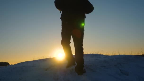 Viajero se levanta en la colina nevada en los rayos del sol. viajero va a la victoria superando las dificultades. turista va en una montaña nevada a la cima, al atardecer. Alpenista viajes senderismo . — Vídeo de stock