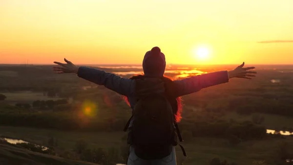 Joven viajera con una mochila llega al borde de un pico de montaña amanecer, levanta las manos en el aire y disfruta de la victoria, hermoso sol y paisaje. chica libre turista viaja en la naturaleza —  Fotos de Stock