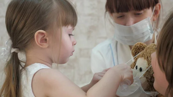 Een klein kind behandelt speelgoeddieren met injecties. Meisje speelt met mama in het ziekenhuis. Game by doctor, verpleegkundige, behandeling met vaccin. gezond meisje en speelgoedbeer. kind speelt in ziekenhuis. — Stockfoto