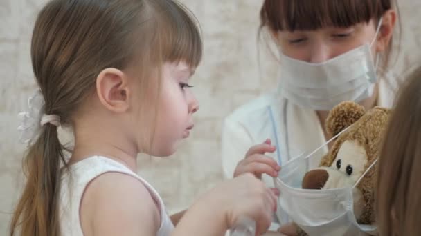 어린아이는 장난감 동물을 주사로 치료 한다. 어린 소녀는 병원에서 엄마와 놀고 있습니다. 의사, 간호사, 백신으로 치료하는 게임. 건강 한 소녀와 장난감 곰. 병원에서 놀고 있는 어린이. — 비디오