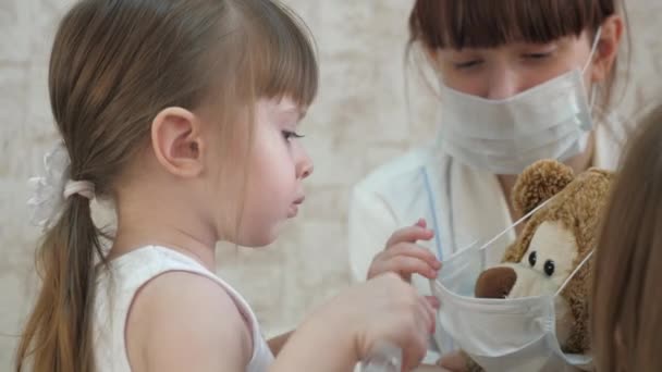 Un niño pequeño trata a los animales de juguete con inyecciones. La niña juega con mamá en el hospital. Juego de médico, enfermera, tratar con la vacuna. niña sana y oso de juguete. niño juega en el hospital . — Vídeo de stock