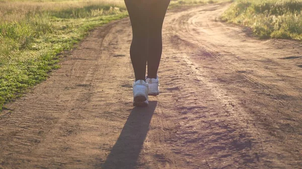 Free young woman is training in summer in the park at dawn. Healthy beautiful girl is engaged in fitness, jogging in country. Jogger girl breathes fresh air. evening run in the beautiful rays of sun. — Stock Photo, Image