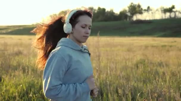 Mujer joven y saludable se está entrenando en verano en el parque al amanecer. gratis hermosa chica se dedica a la aptitud, trotar en el país. La corredora respira aire fresco. noche correr en hermosos rayos de sol . — Vídeos de Stock