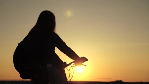 Ciclista solitaria descansando en el parque. Senderista mujer joven sana se encuentra en la colina junto a una bicicleta, disfrutando de la naturaleza y el sol. Chica libre viaja con una bicicleta al atardecer. concepto de aventura y viajes. — Vídeo de stock