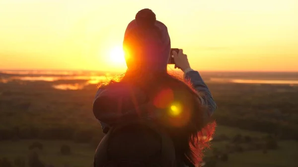 Gesunde, fröhliche Frau reist im Morgengrauen und fotografiert die Natur am Telefon. Junge Touristenbloggerin filmt ein Selfie-Video auf dem Gipfel der Berge mit einem Smartphone mit einer wunderschönen Landschaft. — Stockfoto