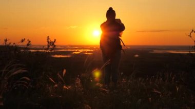 Özgür Genç Kız Turist blogcusu, dağların tepesinde güzel manzaralı bir akıllı telefon kullanarak bir selfie videosu kaydediyor. Sağlıklı, neşeli bir kadın şafak vakti seyahat eder ve doğayı telefonla fotoğraflar..
