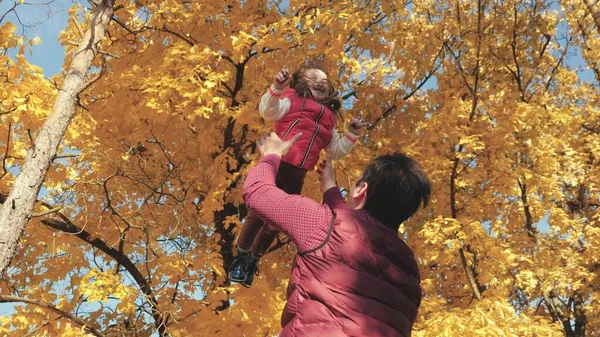 Papá vomita una hija feliz en el cielo en otoño en el parque. familia feliz viaja. Padre e hijo juegan, ríen y abrazan. niño sano en brazos de los padres. Papá está fuera. Concepto de familia feliz — Foto de Stock