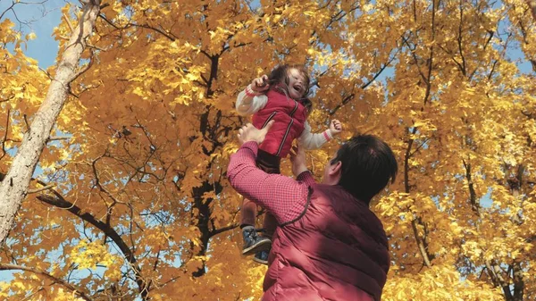 Papá vomita una hija feliz en el cielo en otoño en el parque. familia feliz viaja. Padre e hijo juegan, ríen y abrazan. niño sano en brazos de los padres. Papá está fuera. Concepto de familia feliz — Foto de Stock