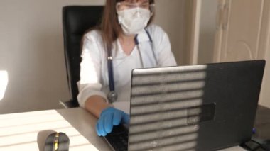 Doktor sanal sohbet kullanarak müşteriyle iletişim kuruyor. Uzaktan tıbbi bakım kavramı. Beyaz önlüklü ve güvenlik gözlüklü kadın doktor laptop, online danışma ve konferans üzerinde çalışıyor.
