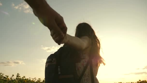 Una joven sana viaja por el campo con su novio, corren a través del campo de un girasol floreciente. chica libre y chico de la mano, caminar en el campo con girasoles al atardecer, tomarse de la mano . — Vídeo de stock