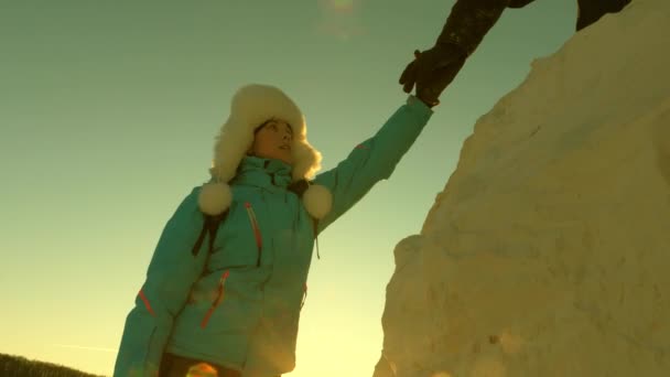 Mladá žena turistka vyleze na horu drží pomocnou ruku. Zdarma žena cestovatel vylézt na horu držet za ruce. horolezci lezou po horách. pracovat v týmu turistů. výlet do hor při západu slunce. — Stock video
