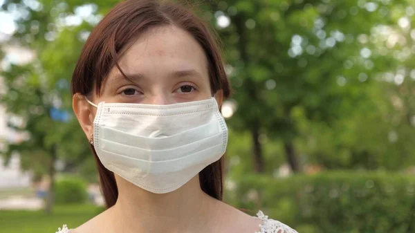 Bouclier facial sur une jeune fille à l'extérieur dans un parc. fille voyage fièrement dans un masque médical. touriste femme protégeant visage contre les virus. aller masqué sur le visage en bas de la rue au magasin pour faire du shopping — Photo