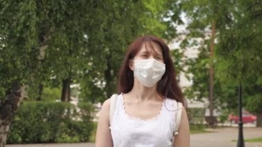 Park 'ta açık havada genç bir kızın yüzünde koruyucu maske var. Şehirdeki kız tıbbi maskeyle seyahat ediyor. Kadın turist yüzünü virüslerden koruyor. Antiviral maskeyle caddenin aşağısındaki dükkana git..