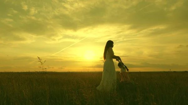 Mamãe circula suas queridas mãos infantis, um bebê saudável em voo ri. criança feliz brinca voando com sua mãe ao pôr do sol. mãe e bebê no parque de verão. conceito de família livre e infância — Fotografia de Stock