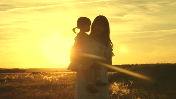 Concetto di infanzia felice. madre sta ballando con un bambino tra le braccia in campo al sole. mamma e figlioletta vorticano nel ballo al tramonto. bambino felice gioca con sua madre al tramonto. concetto di a — Video Stock