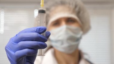 Hastalık aşısı doktor elinde. Hemşire elinde ilaçla bir şırınga tutuyor. Doktor enjeksiyon tedavisi önerdi. Doktor hastaya iğne yapmaya hazır..