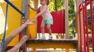 Mutlu çocukluk ve aile kavramı. Küçük çocuk gülüyor ve parktaki oyun alanının tadını çıkarıyor. Çocuk, annesiyle sokakta oynuyor. Anne ve bebek parkta oynuyorlar. Mutlu çocukluk kavramı.
