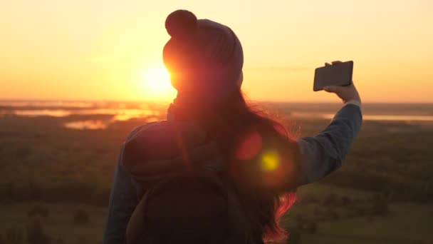 Livre Jovem blogueiro turístico grava um vídeo selfie no topo das montanhas usando um smartphone com uma bela paisagem. Mulher alegre saudável viaja ao amanhecer e natureza fotografia no telefone . — Vídeo de Stock