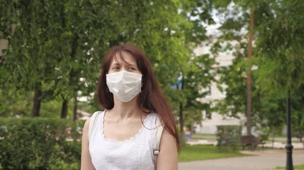 공원 밖에 있는 한 소녀의 얼굴에 보호용 마스크를 쓰고 있었습니다. 길거리의 소녀들은 의료용 마스크를 쓰고 여행 합니다. 암컷 관광객은 바이러스로부터 얼굴을 보호 한다. 가게로 가는 길에 항바이러스제 마스크를 착용하 세요.. — 스톡 사진