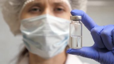 Doktor enjeksiyon tedavisi önerdi. Hastalık aşısı doktor elinde. Covid 19. Bir hemşire elinde ilaçla bir ampul tutuyor. Doktor hastaya iğne yapmaya hazır..