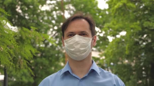 Go masked on street to store for shopping. COVID-19. a man goes to work in city on the street in medical mask. face shield on young man outdoors in park. man tourist protecting face from viruses. — Stock Video