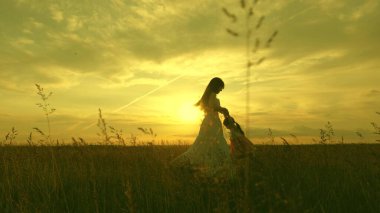 Anne, sevgili çocuğunun ellerinde uçarken sağlıklı bir bebek gülüyor. Mutlu çocuk gün batımında annesiyle uçuyor. Anne ve bebek yaz parkında. Özgür aile ve çocukluk kavramı