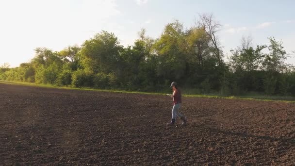 Agricultor mulher com tablet no campo. Um agrônomo feminino verifica a qualidade do grão de semeadura. Um agricultor verifica a qualidade do solo antes de semear. mulher de negócios verifica sua caixa — Vídeo de Stock