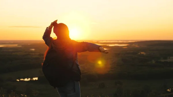 Chica libre turista viaja en la naturaleza solo. joven viajera con una mochila llega al borde de la cima del amanecer, levanta las manos en el aire y gira, disfruta de la victoria, hermoso amanecer y paisaje . —  Fotos de Stock