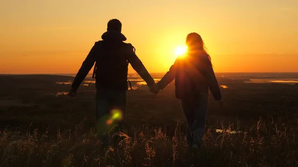旅行者，一个男人和一个女人，背着背包，在黎明的光芒中走到山边，举起双手，享受胜利，美丽的阳光和风景。免费游客旅行。业务团队合作 — 图库照片