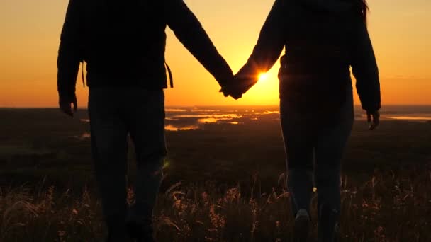 Viaggiatori, un uomo e una donna con lo zaino vanno ai margini della montagna nei raggi dell'alba, alzano le mani in aria e godono della vittoria, del bel sole e del paesaggio. I turisti liberi viaggiano. lavoro di squadra d'affari — Video Stock