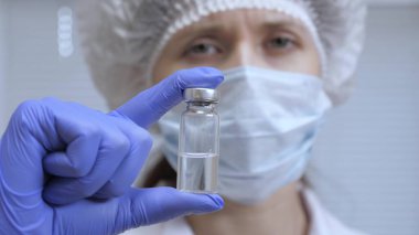 Doktor enjeksiyon tedavisi önerdi. Bir hemşire elinde ilaçla bir ampul tutuyor. Hastalık aşısı doktor elinde. Covid 19. Doktor hastaya iğne yapmaya hazır..