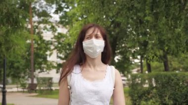 Park 'ta açık havada genç bir kızın yüzünde koruyucu maske var. Şehirdeki kız tıbbi maskeyle seyahat ediyor. Kadın turist yüzünü virüslerden koruyor. Antiviral maskeyle caddenin aşağısındaki dükkana git..