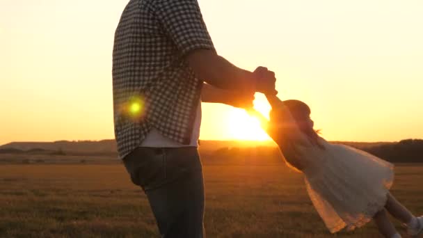 Padre circonda la sua amata figlia in braccio, un bambino sano in volo sorride. bambino gioca volare con papà al tramonto sul campo. Papa 'e il bambino nel parco estivo. concetto di famiglia sana e infanzia — Video Stock