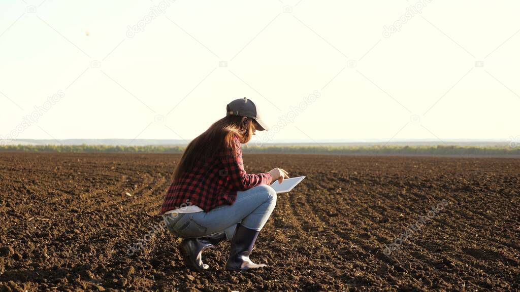 A farmer checks quality of the soil before sowing. woman farmer with a tablet in field holds earth in his hands. girl agronomist checks the quality of sowing grain. business woman checks her field