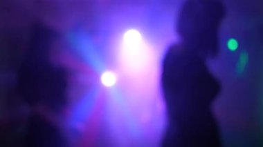 Bir grup genç, şık, çok ırklı insan renkli bir partide eğleniyor ve dans ediyor. Kulüpte eğlenceli bir tatil, insanlar siluetler, dans, müzik, ışık gösterisi.