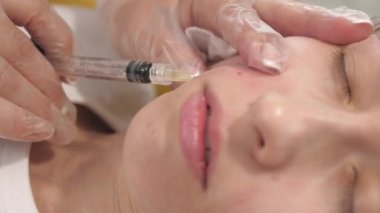 Kozmetik uzmanları tıbbi eldivenlerle bir kadının yüzüne iğne yapar. Güzellik Kliniği. Kadın kozmetik yüz bakımı yaptırıyor. Botoks kolajen enjeksiyonları. gençlik ve güzellik kavramı