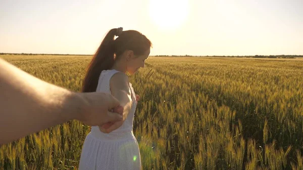 Família de agricultores. uma menina e um homem caminham no campo de trigo, de mãos dadas em raios de sol de verão. Rapariga e homem viajam para fora da cidade no campo. maravilhoso momento romântico entre casal livre no amor . — Fotografia de Stock