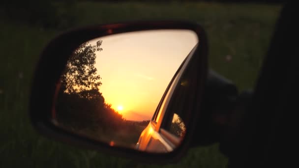 Een prachtige zonsondergang wordt weerspiegeld in de spiegel van de auto. het concept van avontuur en reizen. reizen met de auto buiten de stad. familie reis naar de natuur in een weekend — Stockvideo