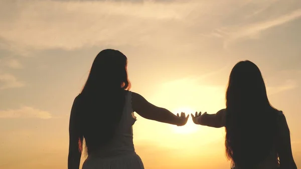 Dotter och mor sträcker ut sina händer till solen. Lycklig familj mamma och dotter på ett fält vid solnedgången. begreppet lycklig barnfamilj. mor och barn går i parken — Stockfoto