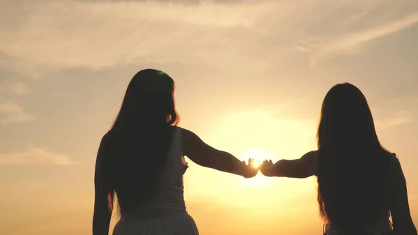 Dotter och mor sträcker ut sina händer till solen. Lycklig familj mamma och dotter på ett fält vid solnedgången. begreppet lycklig barnfamilj. mor och barn går i parken — Stockfoto