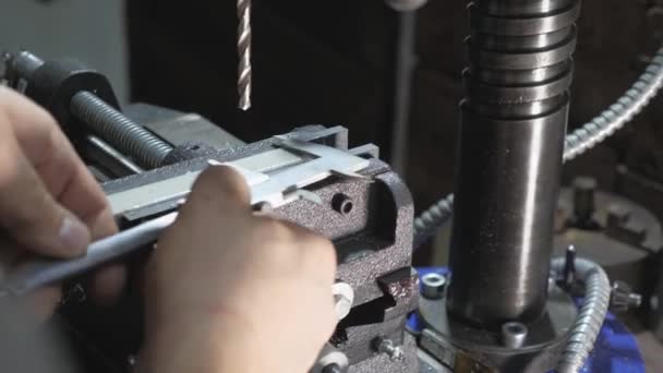 Monteur meet het kaliber detail in de werkplaats. Werknemer in een fabriek in een slotenmakerij. Boormachine, boormachine voor medewerkers op een platte stalen plaat met een tafelboormachine. — Stockvideo