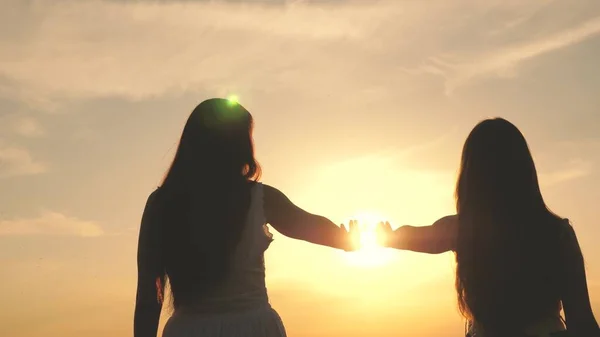 Hija y madre extienden sus manos al sol. Familia feliz mamá e hija en un campo al atardecer. concepto de familia feliz de los niños. madre y bebé están caminando en el parque —  Fotos de Stock